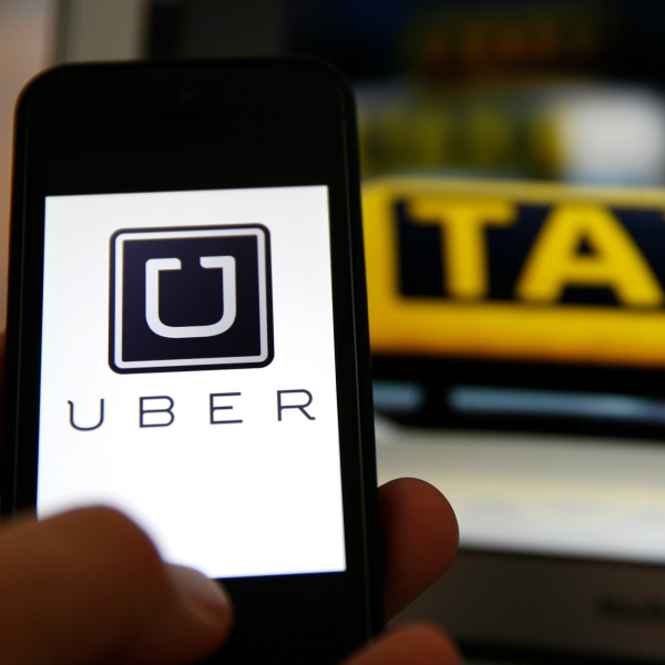 File illustration picture showing the logo of car-sharing service app Uber on a smartphone next to the picture of an official German taxi sign in Frankfurt, September 15, 2014. A Frankfurt court earlier this month instituted a temporary injunction against Uber from offering car-sharing services across Germany. San Francisco-based Uber, which allows users to summon taxi-like services on their smartphones, offers two main services, Uber, its classic low-cost, limousine pick-up service, and Uberpop, a newer ride-sharing service, which connects private drivers to passengers - an established practice in Germany that nonetheless operates in a legal grey area of rules governing commercial transportation. REUTERS/Kai Pfaffenbach/Files (GERMANY - Tags: BUSINESS EMPLOYMENT CRIME LAW TRANSPORT)
