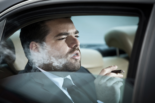 Wealthy man in the back seat of a car smoking